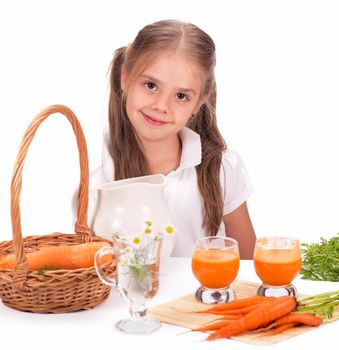 Nice blond baby girl with glass of carrot juice