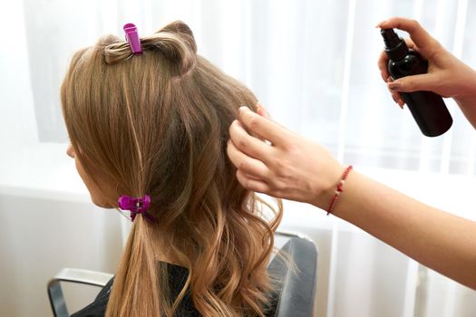 Hairstylist Spraying female Hair in beauty salon