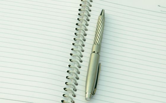 Close up of pen placed on spiral notebook. Full frame shot. High angle view. Business education background.