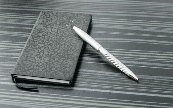 Pen and notebook on office table. Table top view. Corporate business background.