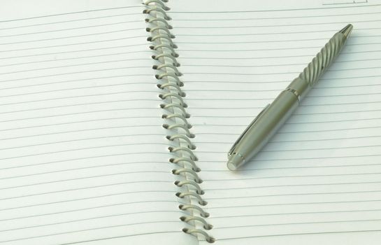 Close up of pen placed on spiral notebook. Full frame shot. High angle view. Business education background.