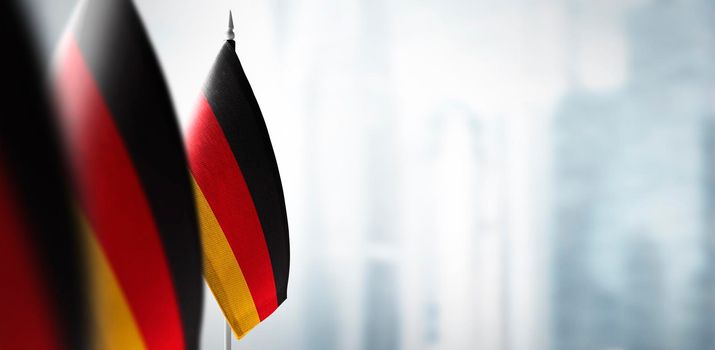 A small flag of Germany on the background of an urban abstract blurred background.