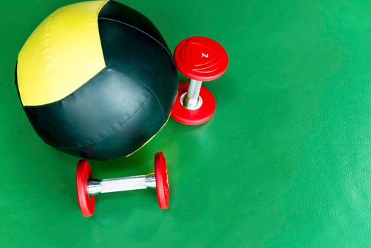 Close up shot of a medicine ball and two lifting dumbbells