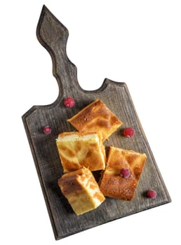 Baked square pieces of pumpkin cheesecake on a wooden board, top view