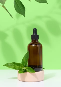 Brown glass bottle with pipette and mint leaves, container for aromatic oils and cosmetics