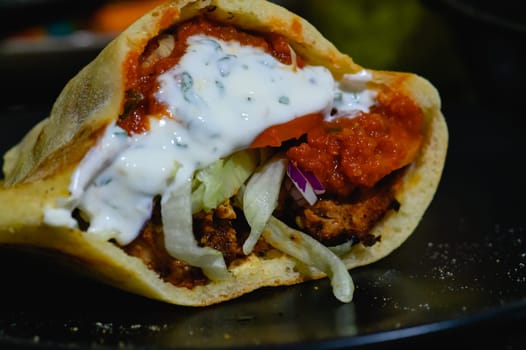 Chicken doner kebab, Turkish style doner kebab sandwich on homemade pita bread with fresh salad and homemade chili sauce and garlic yogurt sauce.