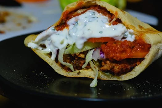 Chicken doner kebab, Turkish style doner kebab sandwich on homemade pita bread with fresh salad and homemade chili sauce and garlic yogurt sauce.