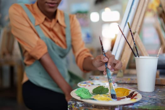 Beautiful american african artist woman painting in art studio at the university classroom.