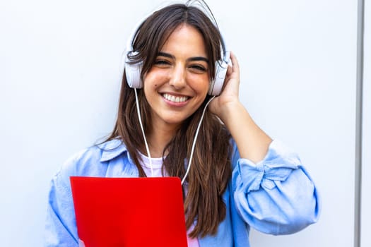 Female brunette college student wearing headphones looking at camera. Young caucasian woman smiling listening to music. Lifestyle concept.