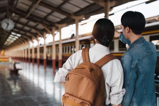 Asian couple at railway station have happy moment. Tourism and travel in the summer.