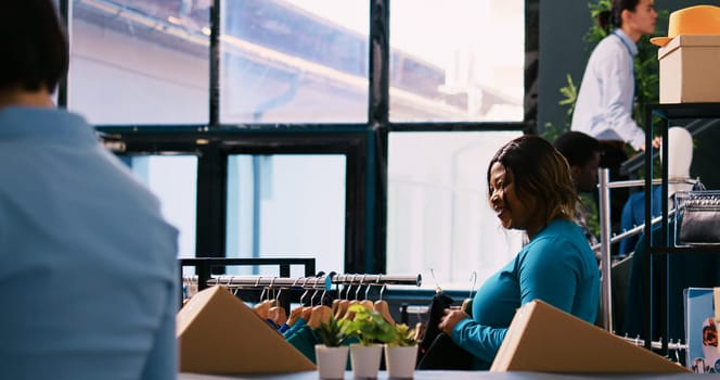 African american customer checking new fashion collection, analyzing clothes material before buying it. Shopaholic woman shopping for fashionable merchandise and accessories in modern boutique