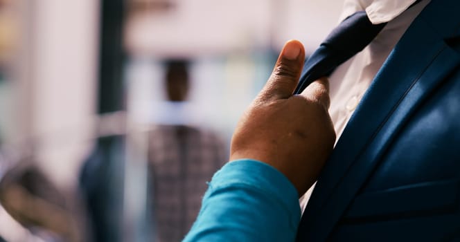 African american customer checking elegant tie fabric, wanting to buy formal suit for husband in modern boutique. Client shopping for new wardrobe, buying trendy merchandise in clothing store