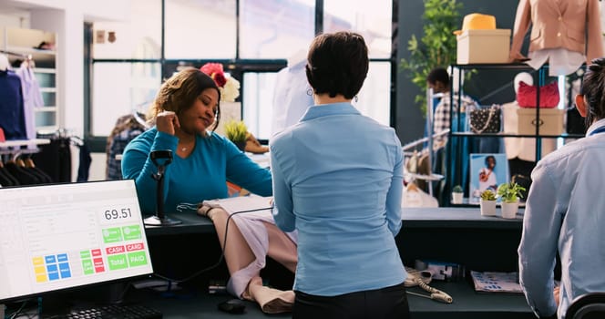 Caucasian manager scanning customer clothes using store scanner in modern boutique. African american woman buying stylish merchandise in shopping mall, wanting new wardrobe. Fashion concept