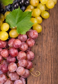 Bunches of fresh ripe red grapes on a wooden textural surface.