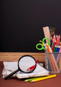 board, books, pencils, opened empty notebook against a dark background