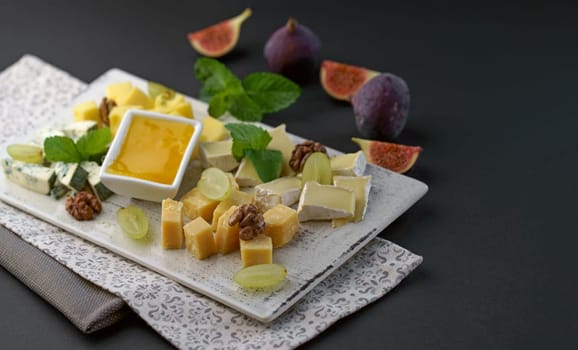 Beautiful delicious camembert cheese, parmesan, brie with grapes and figs on a wooden board. Snacks for wine on holida