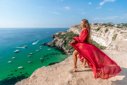 Red Dress Woman sea Cliff. A beautiful woman in a red dress and white swimsuit poses on a cliff overlooking the sea on a sunny day. Boats and yachts dot the background