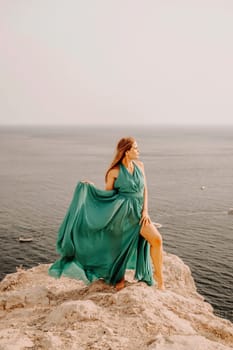 Woman sea green dress. Side view a happy woman with long hair in a long mint dress posing on a beach with calm sea bokeh lights on sunny day. Girl on the nature on blue sky background