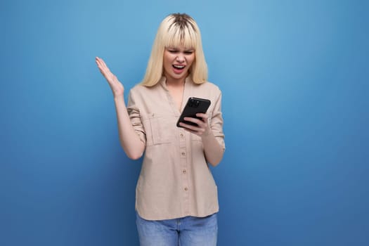 portrait of satisfied pretty blonde european young woman looking at smartphone screen.