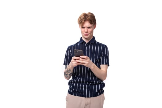 fashionable young white-haired man in blue polo playing phone on white background with copy space.