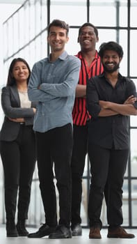 a professional group of diverse business people in casual wear stand in the office with their arms crossed