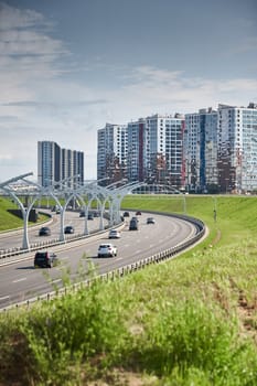 Russia, St.Petersburg, 07 July 2023: Expressway of the western high-speed diameter in clear sunny weather, green lawns along the road, new colourful residential buildings stand on a hillock, lamppost. High quality photo