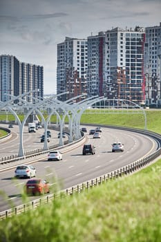 Russia, St.Petersburg, 07 July 2023: Expressway of the western high-speed diameter in clear sunny weather, green lawns along the road, new colourful residential buildings stand on a hillock, lamppost. High quality photo