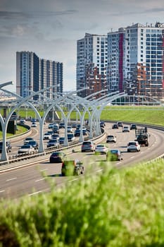 Russia, St.Petersburg, 07 July 2023: Expressway of the western high-speed diameter in clear sunny weather, green lawns along the road, new colourful residential buildings stand on a hillock, lamppost. High quality photo