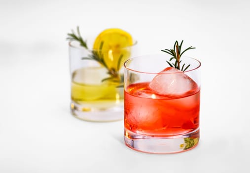 Red cocktail with decoration in a tumbler glass with ice cubes isolated against a white background as a studio shot