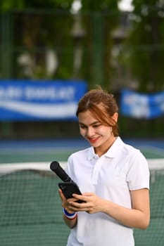 Smiling young woman taking rest after training and using mobile phone. Sport, training and active life concept.