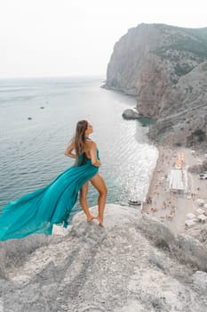 Woman sea green dress. Side view a happy woman with long hair in a long mint dress posing on a beach with calm sea bokeh lights on sunny day. Girl on the nature on blue sky background