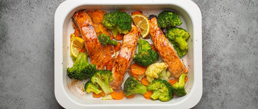 Top view of healthy baked fish salmon steaks, broccoli, cauliflower, carrot in casserole dish. Cooking a delicious low carb dinner, healthy nutrition concept