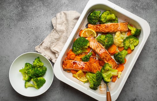 Top view of healthy baked fish salmon steaks, broccoli, cauliflower, carrot in casserole dish. Cooking a delicious low carb dinner, healthy nutrition concept