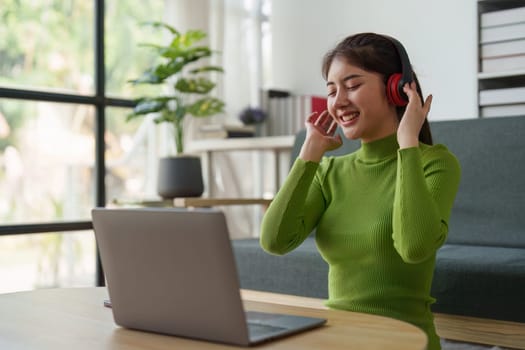 Young asian relaxed smiling pretty woman relaxing with laptop at home. Female feeling joy enjoying with mobile phone on cozy couch.