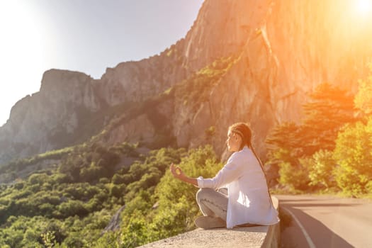 Yoga woman mountains. Profile of a woman doing yoga in the top of a cliff in the mountain. Woman meditates in yoga asana Padmasana.