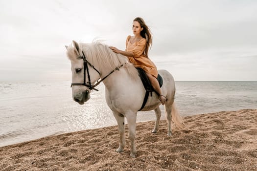 A woman in a dress stands next to a white horse on a beach, with the blue sky and sea in the background