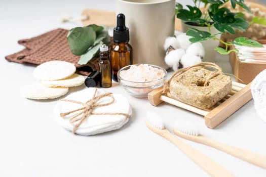 Natural bathroom and home spa tools. Zero waste sustainable lifestyle concept. Bamboo toothbrush, natural shampoo, cotton pads, homemade DIY beauty products in reusable bottles on white background.