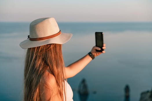 Selfie woman in hat, white tank top and shorts makes selfie shot mobile phone post photo social network outdoors on sea background beach people vacation lifestyle travel concept