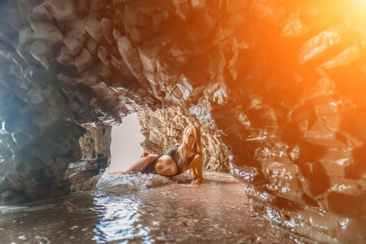 Woman swimsuit sea. Attractive blonde woman in a black swimsuit enjoying the sea air on the seashore around the rocks. Travel and vacation concept