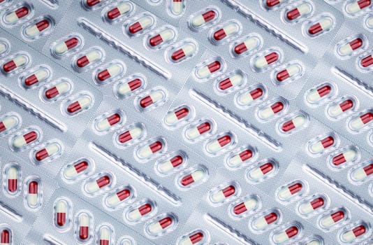 Full frame of white-red capsule pill in aluminum foil blister pack. Prescription drug. Pharmaceutical industry. Pharmaceutical manufacturing industry. Healthcare and medical care. Pharmacy product.