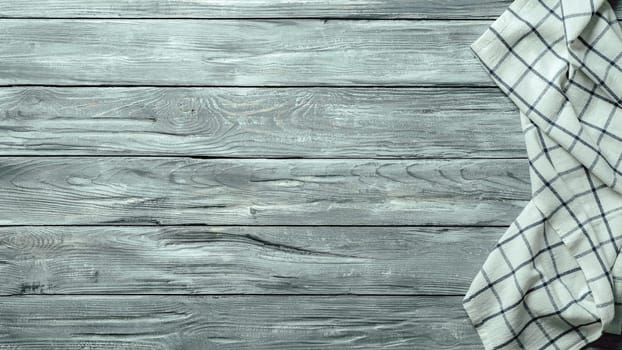 Gray wooden table with linen kitchen towel or textile napkin flat lay. Blue tablecloth on old gray wood tabletop. Copy space for text. Can use as mock up for design.