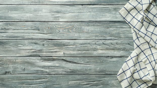 Gray wooden table with linen kitchen towel or textile napkin flat lay. Blue tablecloth on old gray wood tabletop. Copy space for text. Can use as mock up for design. Long horizontal banner