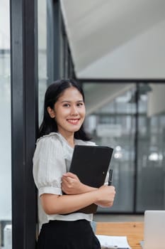 beautiful business asia woman holding files document in office, looking at the camera and smiling.