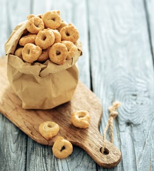 Traditional italian snack taralli or tarallini in paper bag over old gray wooden table. Rustic shot of taralli appetizer with copy space
