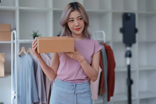 Beautiful Asian woman, blogger, blog, presenting fashion clothes, live video, social media, record her, sell online via digital cameras, sme or small business ecommerce concepts.