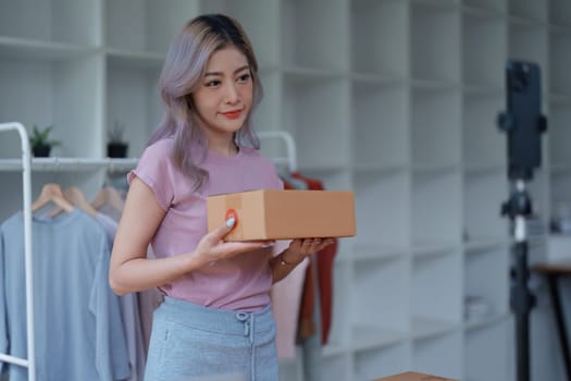 Beautiful Asian woman, blogger, blog, presenting fashion clothes, live video, social media, record her, sell online via digital cameras, sme or small business ecommerce concepts.