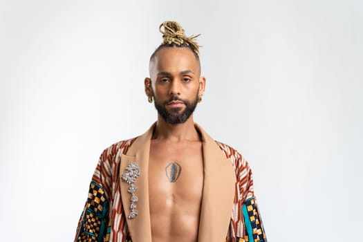 Confident black gay man standing isolated on white, dressed colorful jacket naked torso. Exudes sense of pride and individuality. Diversity power of personal style