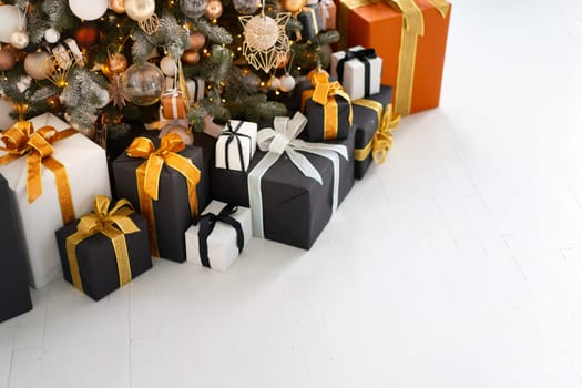 Christmas present gift box stacked close up. Holiday sale concept. Many gift box black, white, orange color with gold ribbon and light garland