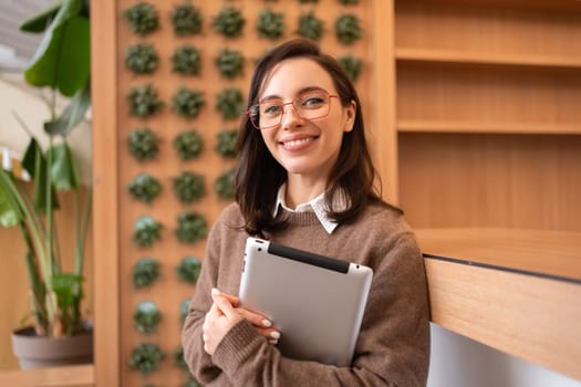 Modern technologies and communication. Portrait of happy woman holding tablet computer standing. Young female person studying or working online on touch pad