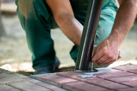 A worker during the installation of a new bench in a city park. New bowls for sitting and relaxing outdoors.